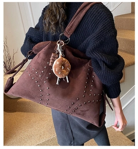 Détail du grand sac à bandoulière en daim marron avec rivets et breloques en peluche