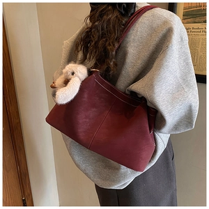 Detail der weinroten Wildleder-Tote-Bag mit Kontrastnähten und Plüschhasen-Anhänger