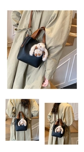 Détail d'un sac seau en cuir noir grainé avec un porte-clé lapin et bandoulière
