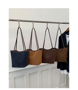 Detail of multi-color minimalist suede tote bags hanging on a rack with leopard print
