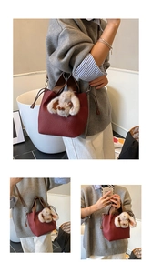 Détail du sac seau en cuir bordeaux avec breloque lapin en peluche et anse marron