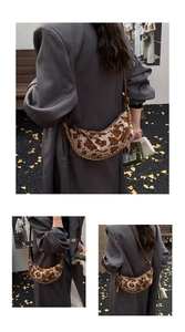 Detailed view of half-moon cow print bag with gold chain and brown leather strap