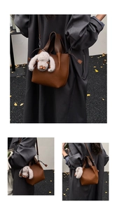 Détail d'un sac seau en cuir marron à motif litchi avec un pendentif lapin en peluche