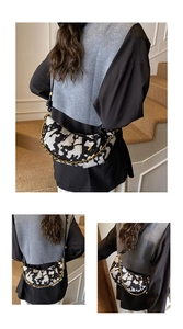 Detail of half-moon shoulder bag featuring black and white jacquard fabric and gold chain