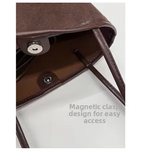 Detail of magnetic snap closure on high-capacity brown suede bucket bag with fine stitching