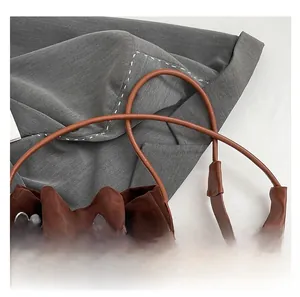 Detail view of dark brown frosted suede bucket bag with drawstring and plush ball charm