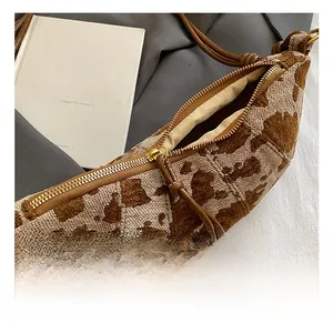 Detailed close-up of knitted jacquard crescent bag with golden zipper and brown pull cord