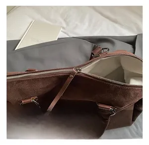 Gros plan d'un sac cabas en daim marron avec rivets et doublure en tissu à chevrons