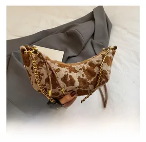 Detail of crescent shoulder bag with brown cow print and golden metal chain strap