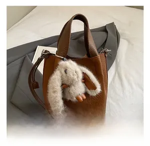 Sac seau en cuir marron grainé orné d'un joli charm lapin en peluche à longues oreilles