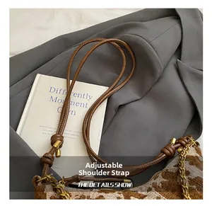 Detail of adjustable leather strap and jacquard fabric texture on stylish shoulder bag