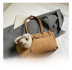 Detail view of earth-tone tote bag with buckle decor and plush rabbit charm on grey suit