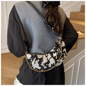 Detail of black and white jacquard crescent bag with leather knot and gold chain strap