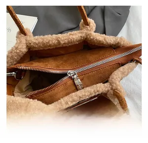 Detail view of brown suede tote bag with faux fur trim and silver zipper closure
