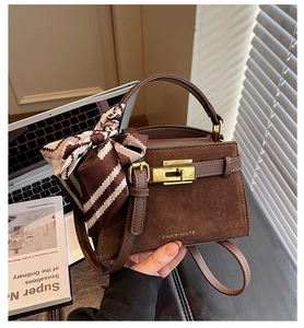 Detail of dark brown leather handbag with metal buckle and striped silk scarf wrap