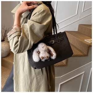 Detail of deep brown matte tote bag with vintage buckle and plush rabbit charm