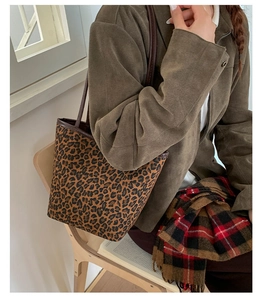 Detailed view of leopard print bucket bag with slim brown shoulder straps on a model
