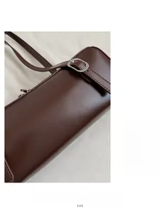 Close-up of brown leather strap with silver buckle detail on a minimalist shoulder bag