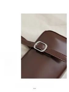 Close-up of dark brown leather underarm bag with adjustable strap and silver metal buckle