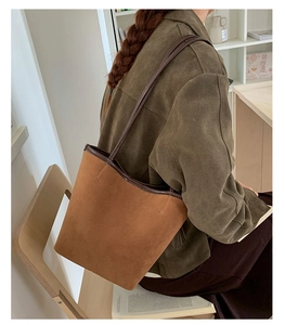 Detail of a brown suede bucket tote bag with slim shoulder straps for daily commute