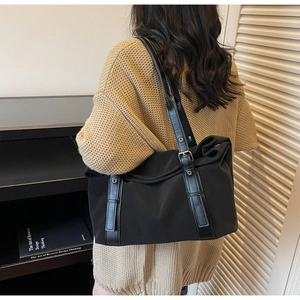 Close-up of black nylon tote bag with leather straps on model in knit sweater