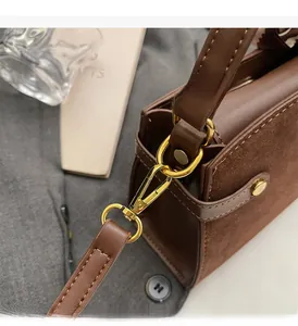 Detailed close-up of premium gold-toned metal hardware and stitching on brown leather bag