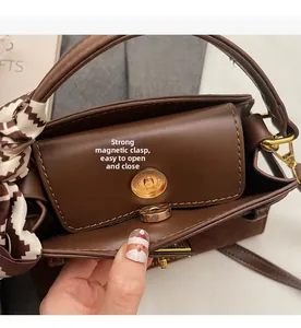 Detail of deep brown handbag showing internal gold magnetic closure and silk scarf handle