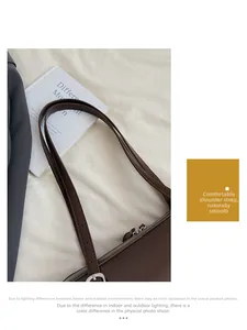 Detail of adjustable shoulder straps and dual silver metal zippers on dark brown handbag