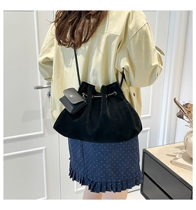 Detail of black suede bucket bag with drawstring and matching small pouch on a model