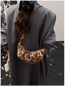 Close-up of cow print crescent bag with gold chain decoration on model shoulder