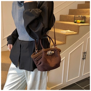 Detail of brown suede bucket bag with faux fur trim and metallic twist-lock closure