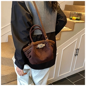 Detail of suede crossbody bag with brown faux fur trim and silver turn-lock closure