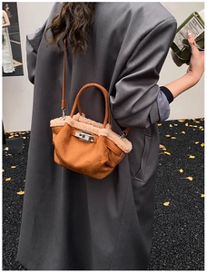 Brown suede tote with beige shearling trim held by a model in a long grey coat