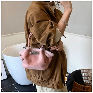 Detail of pink faux suede bucket bag featuring plush trim and silver twist lock closure
