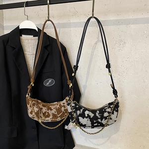 Fashionable half-moon hobo bag with cow print patterns and decorative gold chain