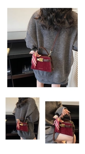 Detail of burgundy textured crossbody bag featuring gold logo and decorative scarf wrap