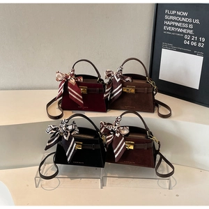 Detail view of four vintage suede square bags with gold buckles and silk scarves