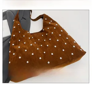 Close-up of brown suede hobo bag with round silver metal rivet details and soft texture