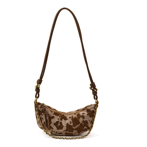 Chic cow print crescent bag with brown leather knotted strap and gold chain accent