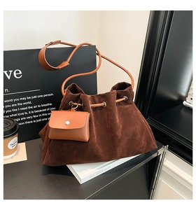 Detail of a brown suede bucket bag with drawstring closure and mini pouch on table