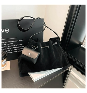 Detail of black suede drawstring bucket bag featuring a detachable leather coin purse
