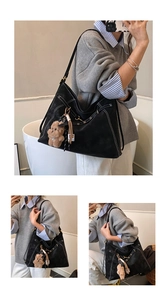 Detailed scene of a women's black matte shoulder underarm tote bag with cute bear charm.