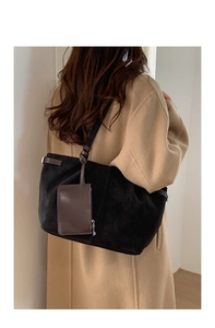 Detail of large black suede tote bag with brown pouch accessory on shoulder