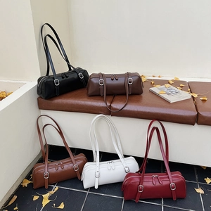 Detail of five cylindrical shoulder bags in various colors with zip and buckle details