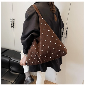 Detail of dark brown suede shoulder bag featuring silver metal rivets and matte texture