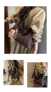 Detailed view of brown suede tote bag with white stitching and plush bear charm