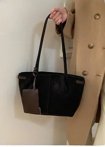 Detail of black suede tote bag with brown leather buckle and mini zipper pouch accessory