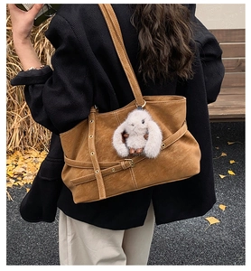 Bolso tote de ante marrón con correas de ojales metálicos y amuleto de conejo blanco