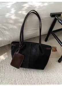Close-up of black suede tote bag with brown leather accents and a small zipper coin pouch