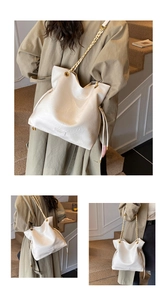Detail of soft cream tote bag featuring a woven gold chain strap and drawstring side